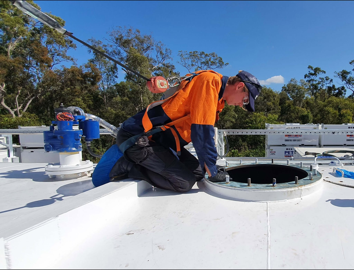 PETRO technician inspecting a fuel tank manway on a rooftop